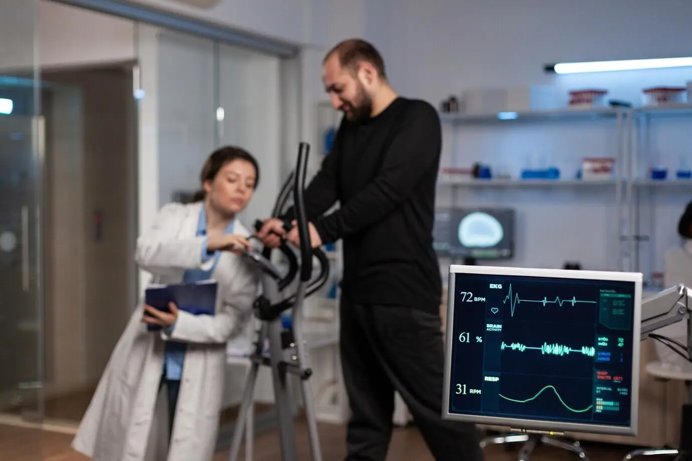 Специалист-врач-исследователь беседует со спортсменом в спортзале, где тренажер отслеживает выносливость организма во время медицинской тренировки в современной лаборатории. Врач-исследователь анализирует данные ЭКГ.