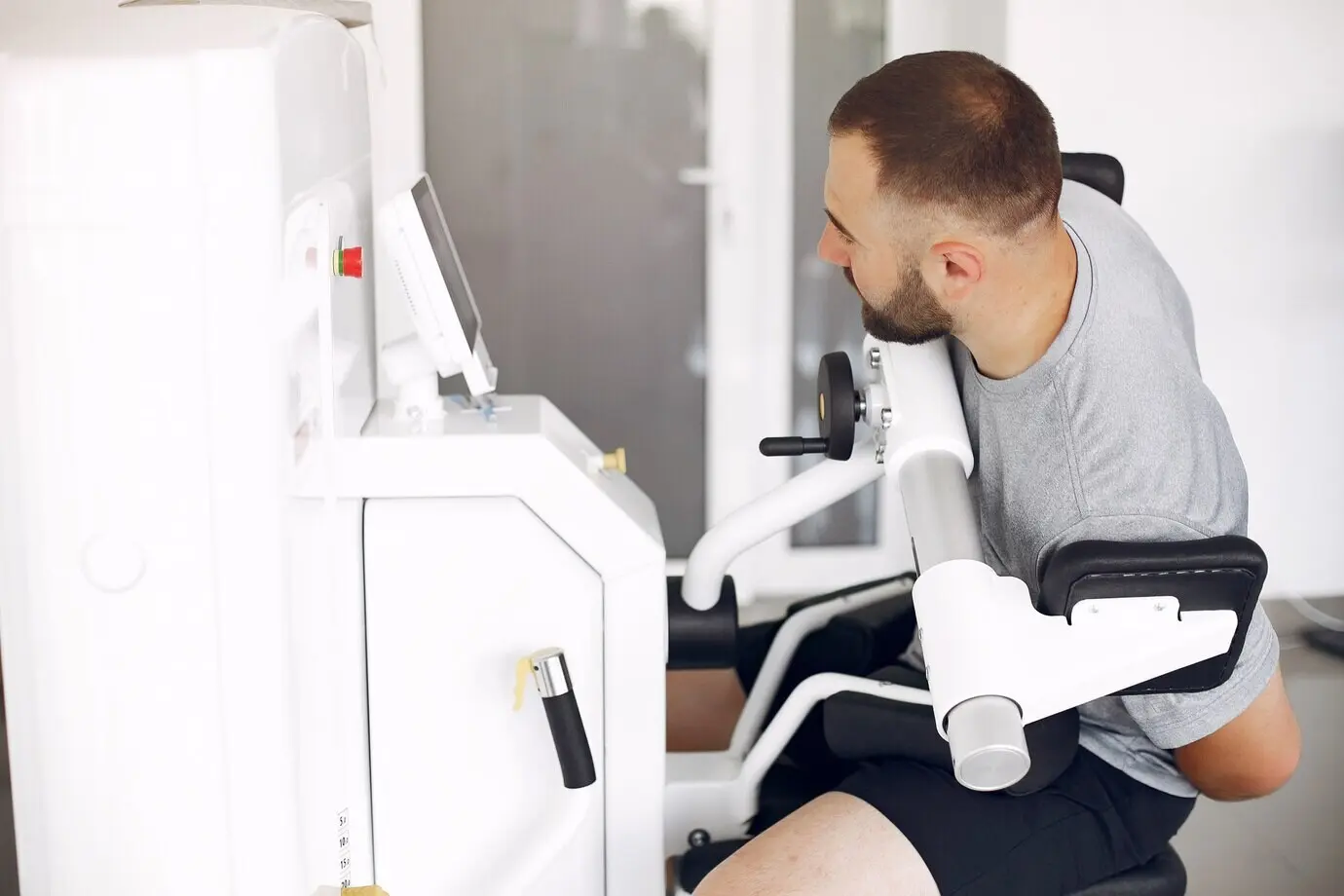 Бородатый мужчина проходит реабилитацию после травмы в физиотерапевтической клинике.